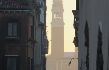Bell tower behind the Bridge of Sighs between two apartments in late-afternoon Venice.